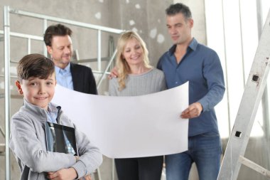 Gülümseyen mutlu çocuklu dijital tabletli bir aileye ev tasarımı planları gösteren mimar. Ev yapımı hedef kavramı. Ev görünümü, iç dekorasyon ve ev düzeni hakkında konuşmak için iç inşaat sahasında buluşacağız.