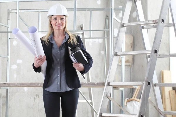 戴着虚拟现实眼镜 面带微笑的女建筑师或建筑工程师戴着头盔 并在建筑工地内放置有梯子和脚手架的蓝图 — 图库照片