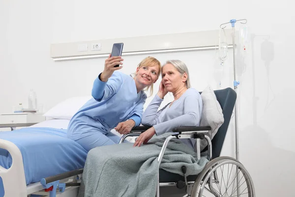 Nurse Helps Cell Phone Contact Elderly Lady Family Wheelchair Bed — Stock Photo, Image