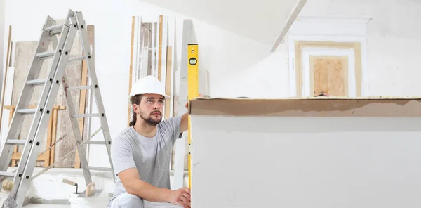 Bauarbeiter Stuckateur Schaut Auf Wasserwaage Und Überprüft Mauer Auf Baustelle — Stockfoto