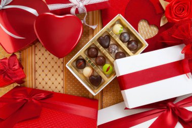 Sevgililer Günü arkaplanı, hediye kutuları çikolata ve kırmızı kalp şeklinde metal kutular, fiyonklar ve kurdeleler, süs kumaşının üst görüntüsü. Tebrik kartı ya da pasta afişi şablonu için