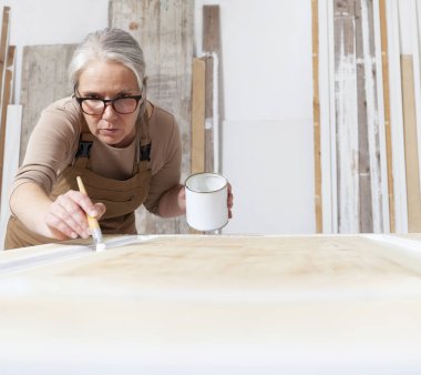Ahşap el sanatları, kadın marangoz fırça ve boya kavanozu ile resim atölyede beyaz kapı, giysi ve gözlük, iç mimar, restorasyon, diy ve el yapımı iş konsepti