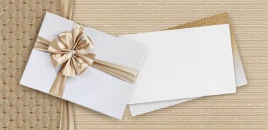 Hediye kartı, bej kurdeleli hediye kutusu zarif kumaş arka planı, üst görünüm ve kopyalama alanı şablonu, en iyi dilekler ve alışveriş konsepti için kullanışlı düzen