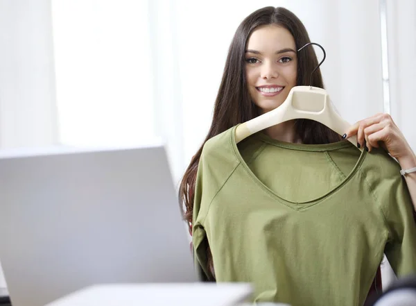 若い女性は笑顔とカメラにTシャツを示し オンラインで服を販売 — ストック写真