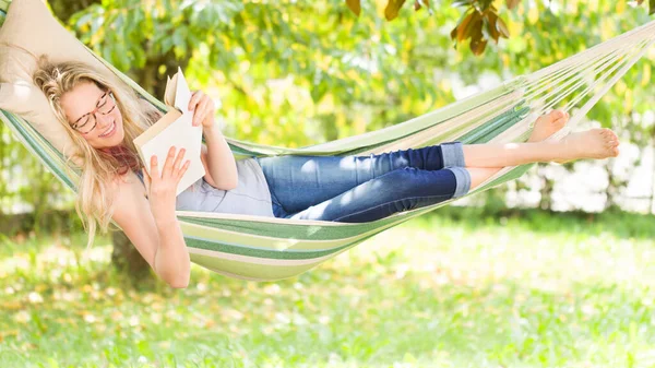 Mujer Rubia Sonriente Con Anteojos Leyendo Libro Relajándose Hamaca Jardín —  Fotos de Stock