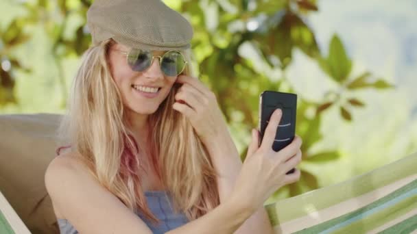Mujer Rubia Sonriente Con Gafas Sol Usando Smartphone Tumbada Relajada — Vídeos de Stock
