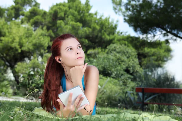 Estudiante en parque con libro digital y auriculares —  Fotos de Stock