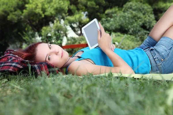 Estudiante en parque con libro digital y auriculares — Foto de Stock