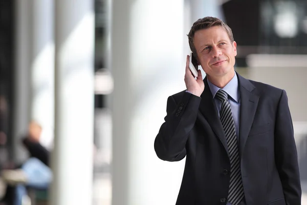 Hombre de negocios sonriente hablando por teléfono durante un viaje de negocios —  Fotos de Stock