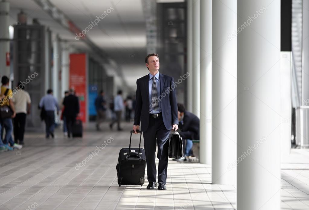 Businessman walking with trolley through the crowd on a business trip