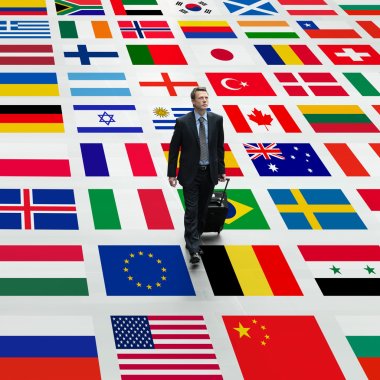 Business man travels the world, walking on a background of international flags