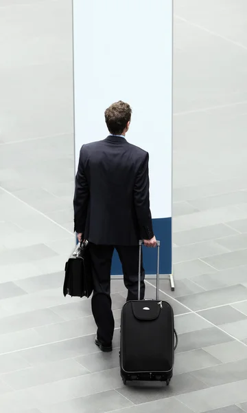 Biznesmen, który wybiera przed znakiem z walizką i wózek — Zdjęcie stockowe