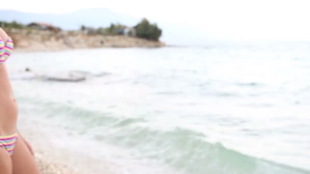 Жінка в купальнику ходить на пляжі і занурюється в море — стокове відео
