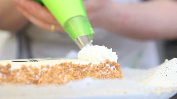 Ręce worka ciasta udekorować tort odrobina bitej śmietany — Wideo stockowe
