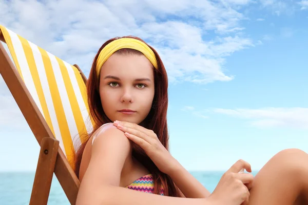 Frau sitzt am Strand und setzt die Sonnencreme auf — Stockfoto