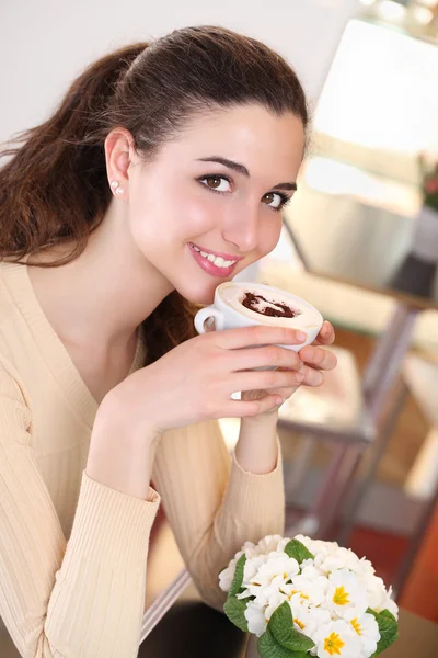 Улыбающаяся девушка в кофе пьет чашку капучино — стоковое фото