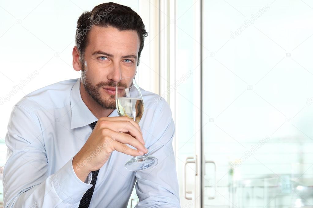 Beautiful man drinking champagne with intriguing look