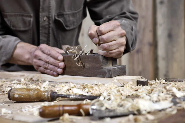 Manos del plano del carpintero en el banco de trabajo en carpintería — Foto de Stock