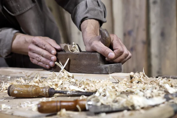 Manos del plano del carpintero en el banco de trabajo en carpintería — Foto de Stock