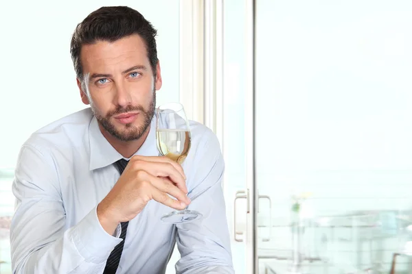 Homem bonito bebendo um copo de vinho espumante branco, no bar — Fotografia de Stock