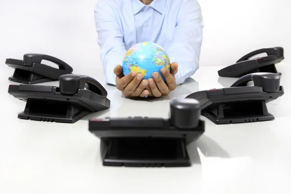 Ruce glóbus s telefony kanceláři na stole, globální koncepce — Stock fotografie