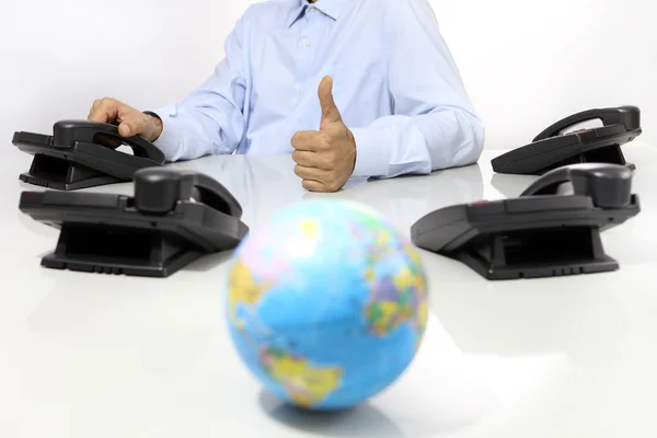 Globe och som hand med office telefoner på skrivbord, stödja globala internationella koncept — Stockfoto