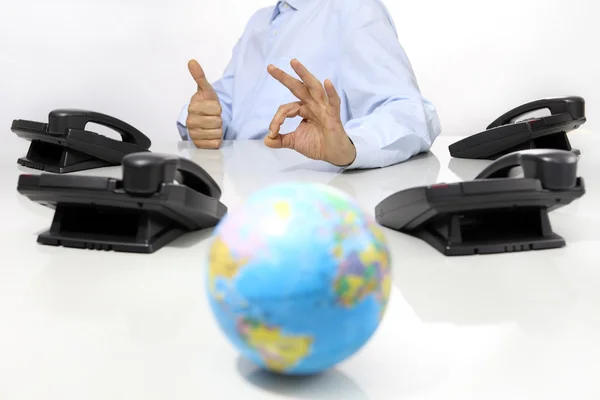 Globe, és a kezét a Hivatal telefon, íróasztal, mint globális nemzetközi támogatási koncepció — Stock Fotó