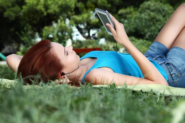 School meisje in het park met slimme telefoon en oortelefoon — Stockfoto