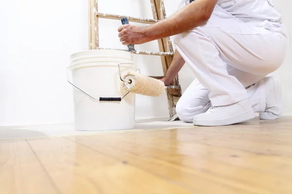Pintor homem no trabalho com um rolo, balde e balança, vista inferior — Fotografia de Stock