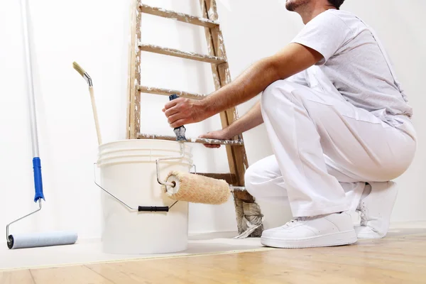 Pintor homem no trabalho com um rolo, balde e balança, vista inferior — Fotografia de Stock