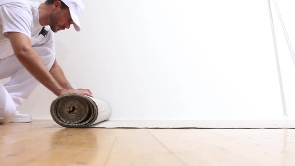 Pintor hombre en el trabajo, rueda el cartón en el suelo — Vídeos de Stock