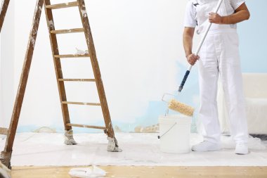 Painter man at work takes the color with paint roller from bucket clipart