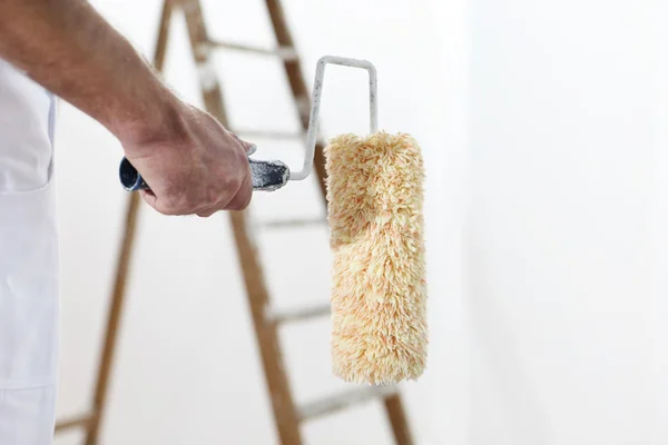 Schilder mens op het werk met een verfroller en ladder, close-up Stockfoto