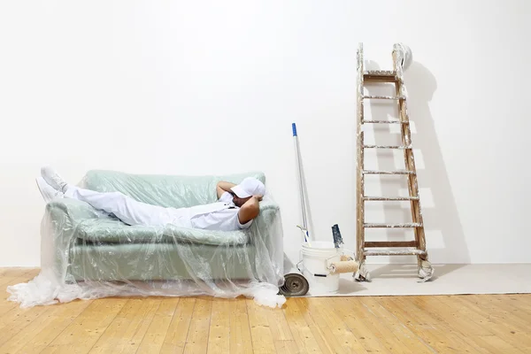 Pittore uomo al lavoro, finito di lavorare e sdraiato sul divano — Foto Stock
