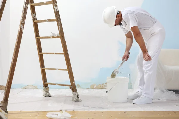 Peintre homme au travail prend la couleur avec pinceau de peinture du seau — Photo