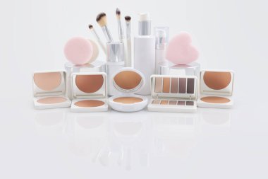 Beyaz parlak yansıtıcı yüzeyde izole edilmiş makyaj ve güzellik ürünleri. Güzellik mağazası reklamları, online alışveriş ve Noel hediyesi fikirleri.