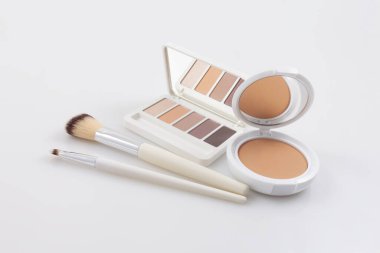 Makyaj ve kozmetik ürünleri, pudra ve göz farı paleti yumuşak fırçalarla açıldı. Beyaz yüzeyde izole edilmiş. Mağaza reklamları, online alışveriş ve Noel hediyesi fikirleri.