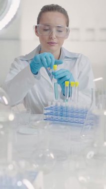 Laboratuvarda pipet ve tüp kullanarak çalışan kadın bir bilim adamı. Biyoteknoloji, ilaç, tıbbi ve mikrobiyoloji araştırmaları için sıvı örneklerinin karıştırılması ve incelenmesi.