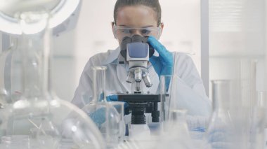 Laboratuvarda mikroskopla çalışan kadın bir bilim adamı. İlaç, tıbbi ve mikrobiyoloji araştırmaları.