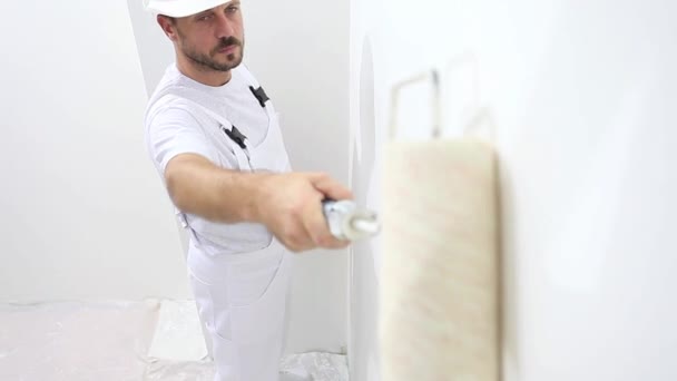 Pintor hombre en el trabajo, con la pared de pintura del rodillo, concepto de la casa del pintor — Vídeos de Stock