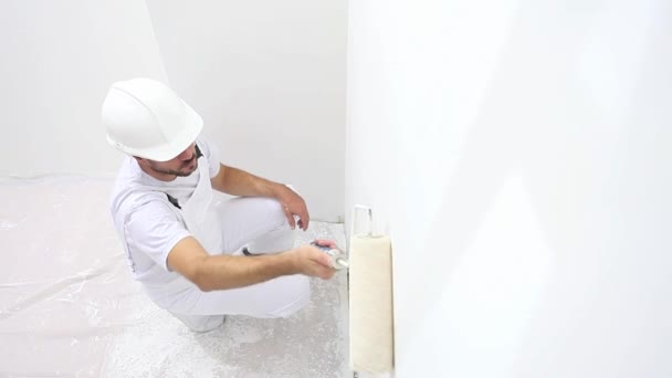 Pintor hombre en el trabajo, con la pared de pintura del rodillo, concepto de la casa del pintor — Vídeos de Stock