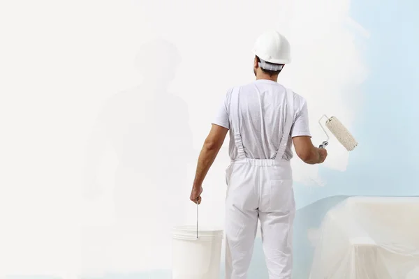 Pittore uomo al lavoro con un rullo di vernice e secchio, pittura murale Foto Stock Royalty Free