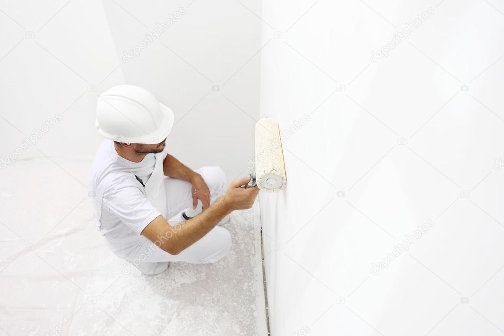 painter man at work with a paint roller, wall painting concept