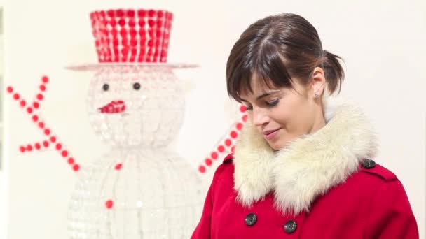 Χριστούγεννα γυναίκα ανοίγει την τσάντα και έκπληκτος χαμόγελα, με χιονάνθρωπο στο παρασκήνιο — Αρχείο Βίντεο