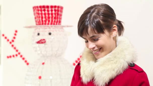 Mulher de Natal abre saco com presente e sorrisos, com boneco de neve no fundo — Vídeo de Stock