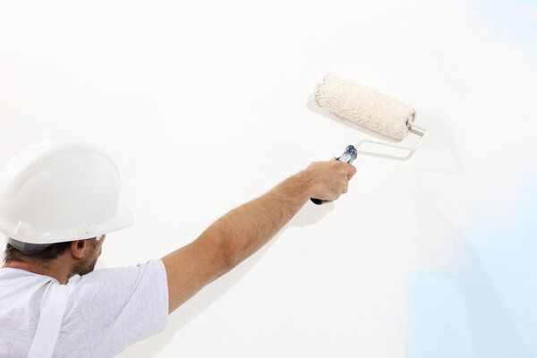 painter man at work with a paint roller, wall painting concept