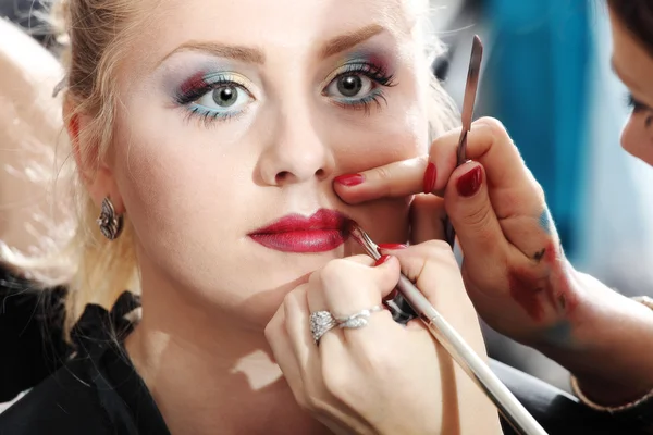 Maquillador aplicando lápiz labial sobre labios modelo con pincel — Foto de Stock