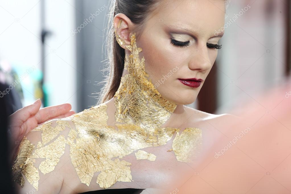make up  model at mirror, gilded body paint