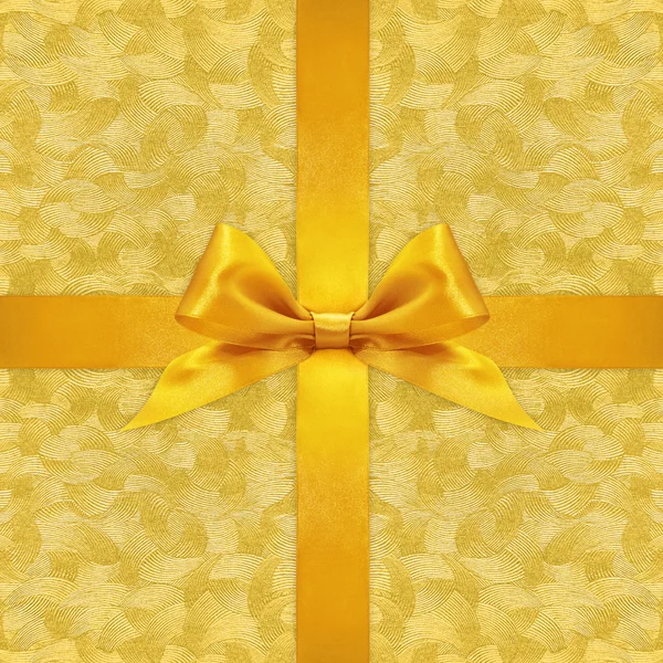 Shiny golden satin ribbon bow on gold background — Stock Photo, Image