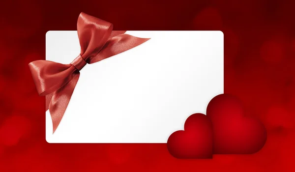 Gift card con fiocco a nastro rosso e cuori isolati su backgro rosso — Foto Stock